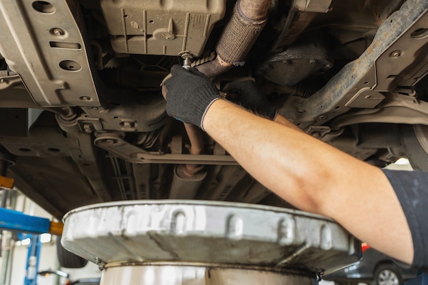 Un Empleado Del Servicio De Coches Destuerce El Tapón De Drenaje De Aceite  En El Cárter De Un Coche De Pasajeros Con Una Llave Din Imagen de archivo -  Imagen de aprieta