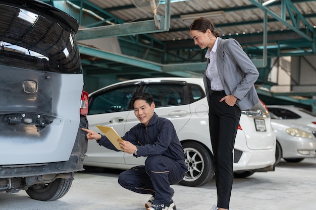 Mecánico de automóviles asiático explicando la lista de verificación de reparación de automóviles a una mujer cliente en un servicio de garaje de automóviles