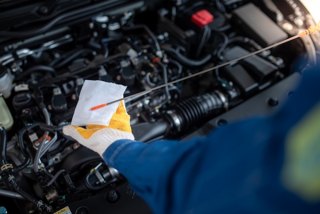 Un mecánico de automóviles asiático en un taller de reparación de automóviles está revisando el motor. Para los clientes que usan automóviles para servicios de reparación, el mecánico trabajará en el garaje.