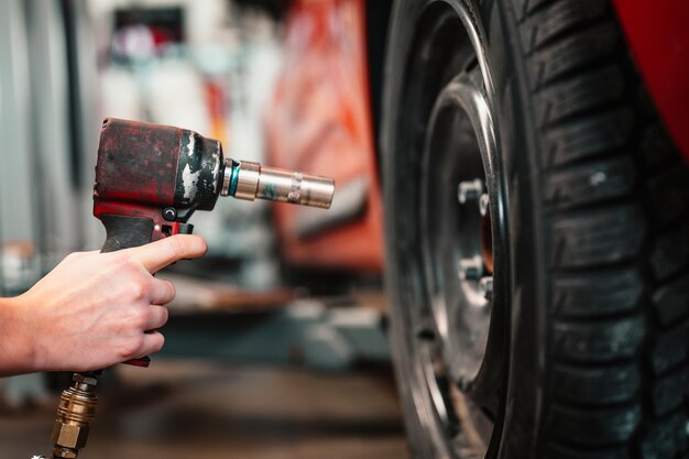 Mecánico de automóviles cambiando neumáticos de aleación de ruedas Trabajando en garaje Servicio de automóviles Proceso de verificación del estado de los neumáticos reemplazados en un centro de servicio Industria del automóvilxA