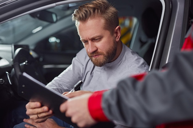 Mecánico de automóviles y cliente con informe en portapapeles