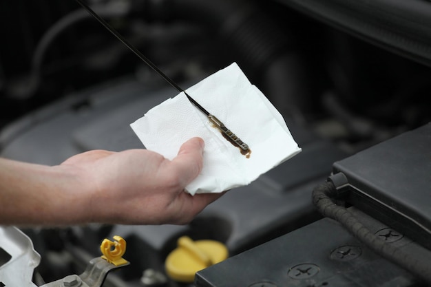 Mecánico de automóviles comprobando la varilla de nivel de aceite del motor en el coche