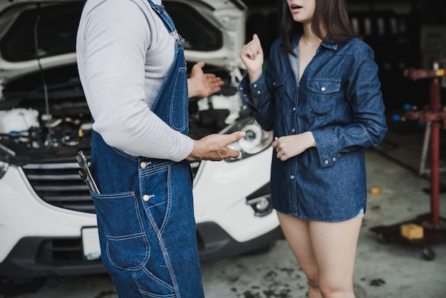 Foto mecánico de automóviles confiable hablando con una clienta.