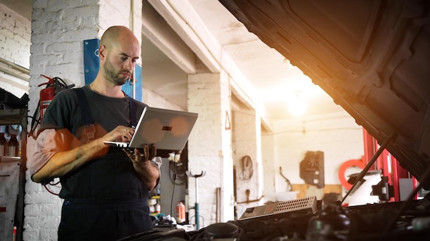 El mecánico de automóviles diagnostica un automóvil usando un primer plano del taller de automóviles de la computadora