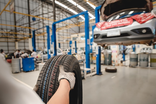 El mecánico de automóviles está cambiando neumáticos nuevos en la tienda de servicio de cambio de neumáticos