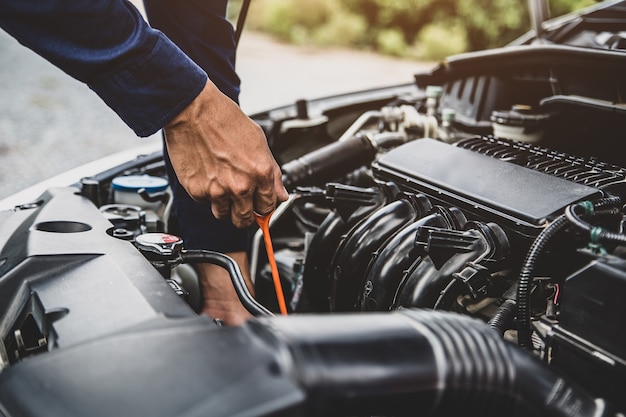 El mecánico de automóviles está revisando el nivel de aceite del motor del vehículo para cambiar el aceite del motor del automóvil