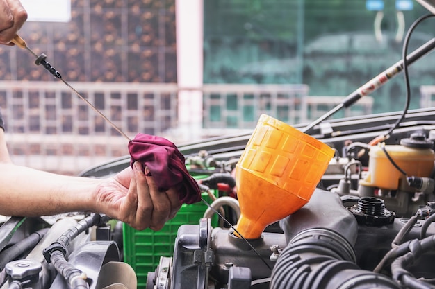 El mecánico de automóviles está verificando el nivel de aceite del motor del indicador de nivel de aceite del motor del automóvil, la industria automotriz y los conceptos de garaje.