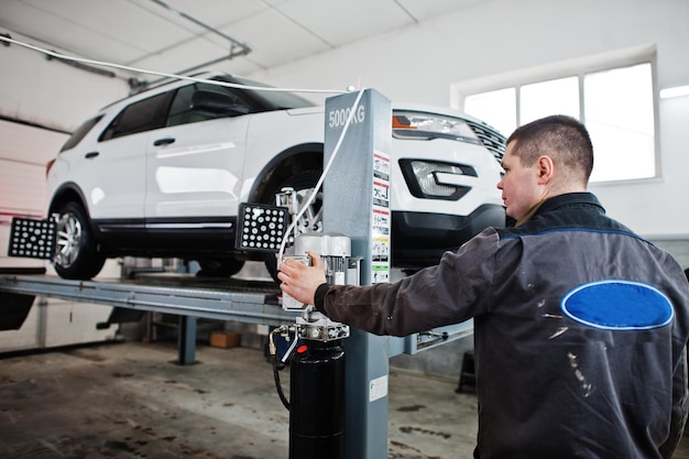 El mecánico de automóviles establece un automóvil SUV americano para el diagnóstico y la verificación de la inclinación de la configuración en el taller de la estación de servicio