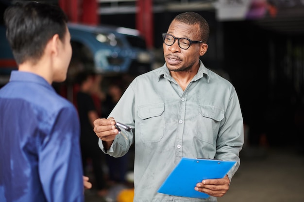 Foto mecánico de automóviles hablando con el cliente explicando qué piezas se deben pedir