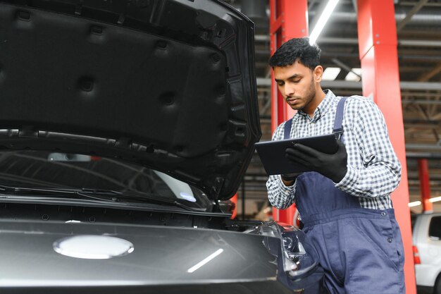 Mecánico de automóviles indio feliz en traje azul