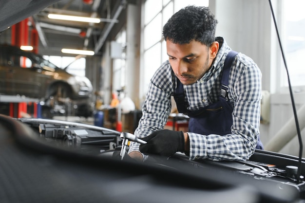Mecánico de automóviles indio feliz en traje azul