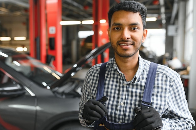 Mecánico de automóviles indio feliz en traje azul