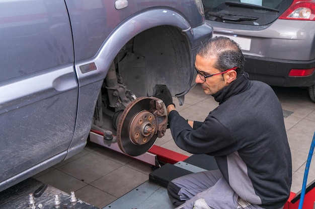 Mecánico de automóviles inspeccionando el sistema de frenos en el taller