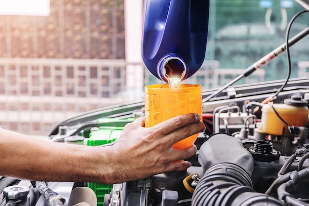 Foto el mecánico de automóviles está llenando el aceite del motor de los coches dentro del centro de reparación de automóviles