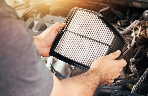 Foto un mecánico de automóviles lleva un filtro de aire de repuesto para el mantenimiento del motor del automóvil