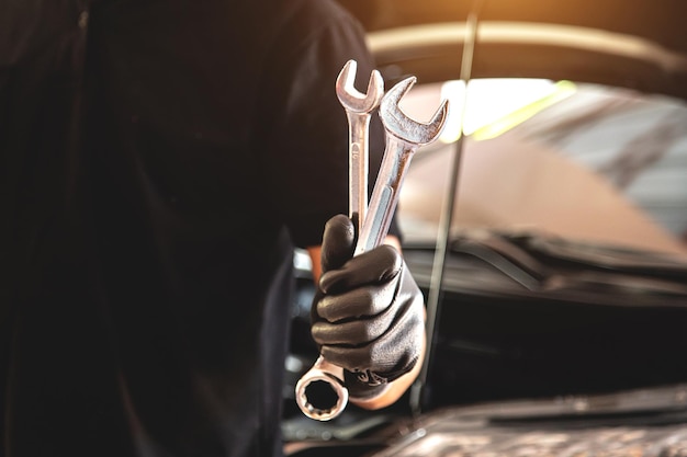 Mecánico de automóviles de mano de primer plano sosteniendo la llave para reparar el motor del automóvil