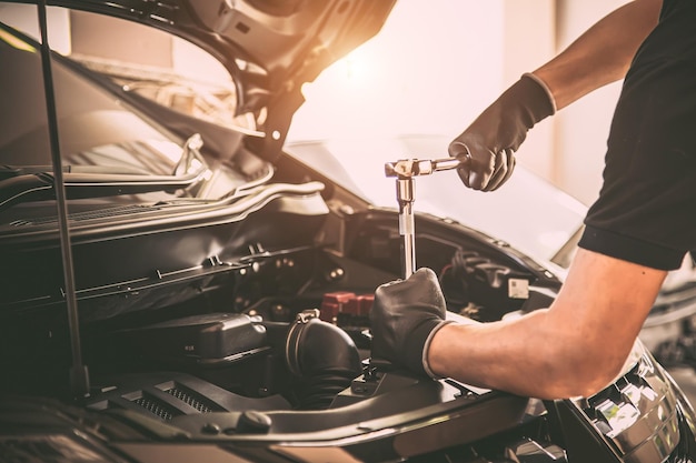 Foto mecánico de automóviles de mano de primer plano usando la llave para reparar el problema del motor del automóvil