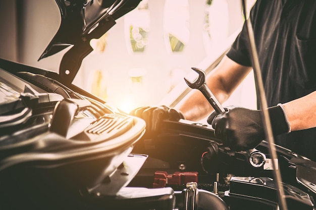 Mecánico de automóviles de mano de primer plano usando la llave para reparar el problema del motor del automóvil