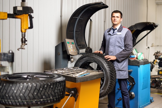 Mecánico de automóviles profesional equilibrando la rueda del automóvil en el equilibrador en el servicio de reparación de automóviles.