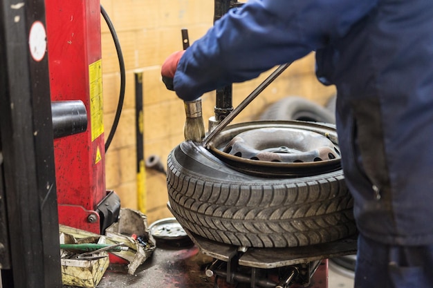 Mecánico de automóviles profesional que reemplaza el neumático en la rueda en el servicio de reparación de automóviles