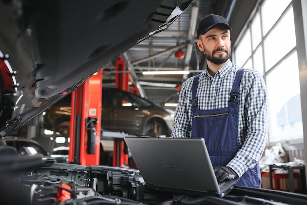 Foto mecánico de automóviles profesional que trabaja en el servicio de reparación de automóviles