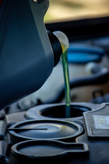 Un mecánico de automóviles que cambia el aceite vierte aceite en el motor de un automóvil.