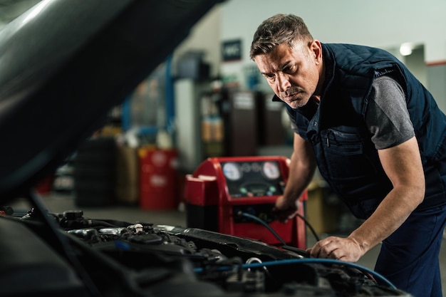 Mecánico de automóviles que mantiene el sistema de aire acondicionado de un automóvil en el taller de reparación