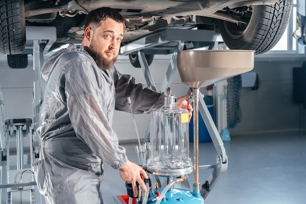 Mecánico de automóviles que reemplaza el aceite en el motor del motor. Taller de servicio automático