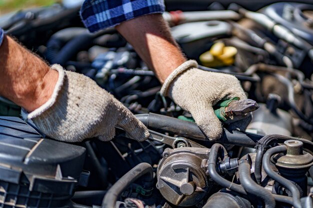 Mecánico de automóviles que repara el motor de un automóvil con una llave. Servicio de reparación