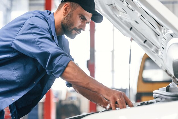 Foto mecánico de automóviles que trabaja en garaje servicio de reparación