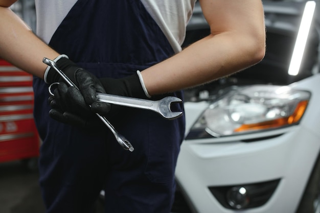 Mecánico de automóviles que trabaja en el motor del automóvil en el taller mecánico Servicio de reparación