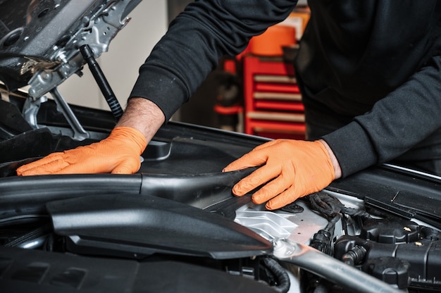 Mecánico de automóviles que trabaja y repara el motor del automóvil en el garaje de mecánica. Servicio de auto.