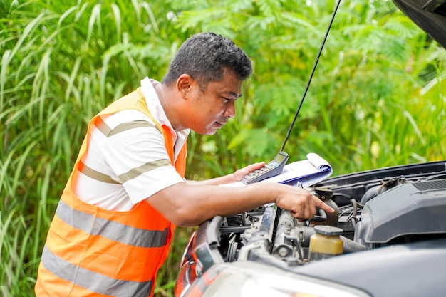 El mecánico de automóviles realiza una comprobación básica del motor para las reparaciones de una avería del motor