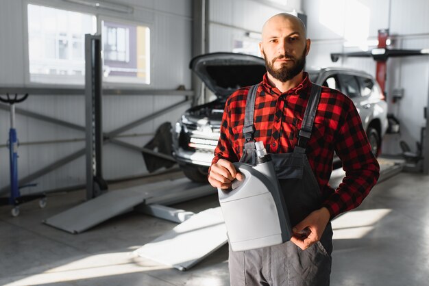 Mecánico de automóviles reemplazando y vertiendo aceite nuevo en el motor del automóvil