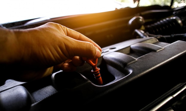 Foto el mecánico de automóviles tira de la varilla medidora para comprobar el nivel de aceite del motor concepto de servicio de mantenimiento de automóviles