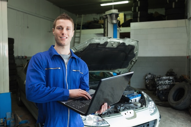 Mecánico de automóviles trabajando en la computadora portátil