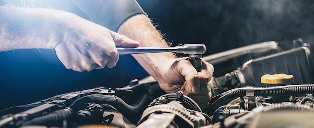 Mecánico de automóviles trabajando en el motor del automóvil en el garaje mecánico. Servicio de reparación. primer plano auténtico, tamaño pancarta