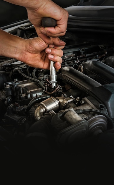 Mecánico de automóviles trabajando en el motor del automóvil en el servicio de reparación de garaje de mecánicos