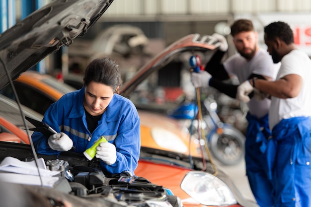 Foto mecánico de automóviles trabajando en un taller de reparación de automóviles inspeccionando el funcionamiento del aire acondicionado de los automóviles