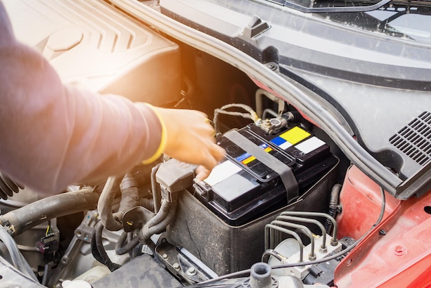 Foto el mecánico de automóviles usa un voltímetro para verificar el nivel de voltaje de la batería del automóvil