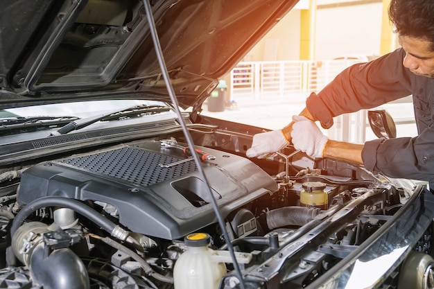 Mecánico de automóviles usando una tuerca de llave en el motor del automóvil.