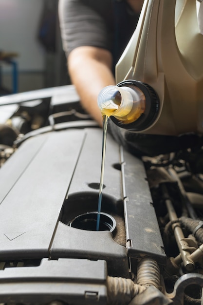 Mecánico de automóviles vierte aceite en el motor