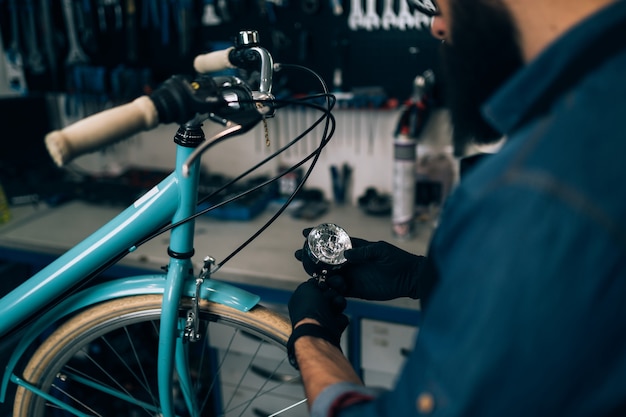 Mecánico de bicicletas de barba joven reparando bicicletas en un taller.