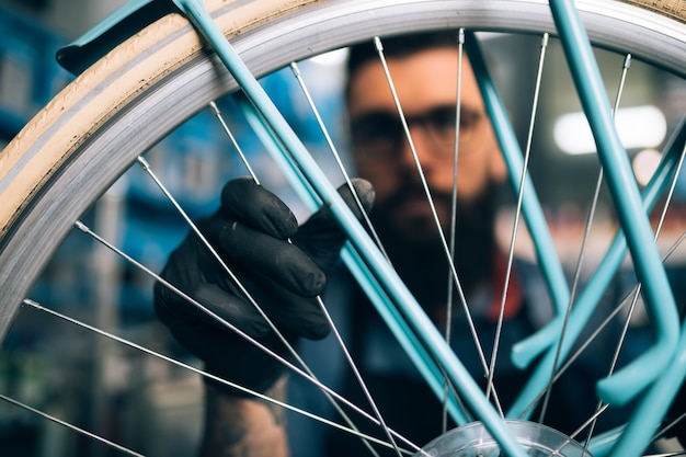 Mecánico de bicicletas de barba joven reparando bicicletas en un taller.