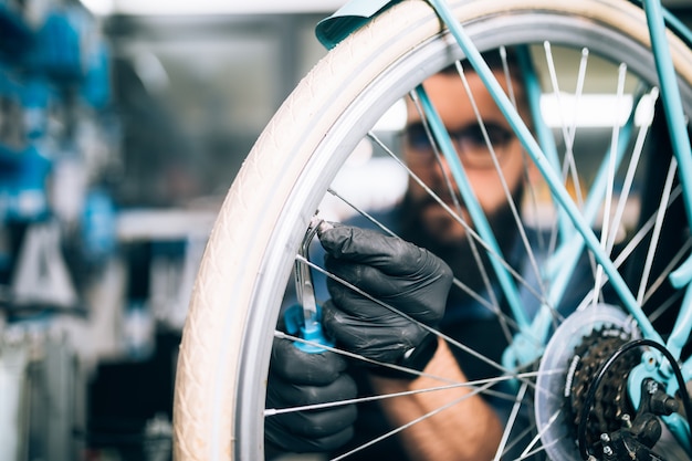 Mecánico de bicicletas de barba joven reparando bicicletas en un taller.