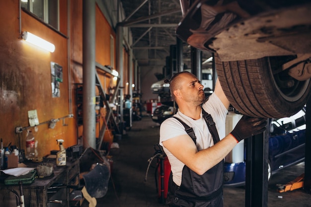 Mecánico cambiando la rueda del coche en un taller de reparación de automóviles