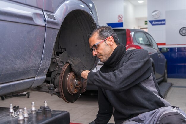 Foto el mecánico comprueba los frenos de disco del coche.