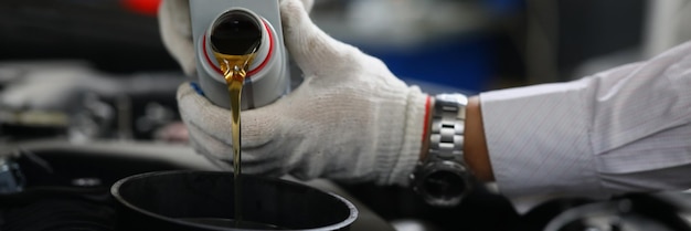 Mecânico de automóveis derrama óleo de motor em closeup de motor de carro