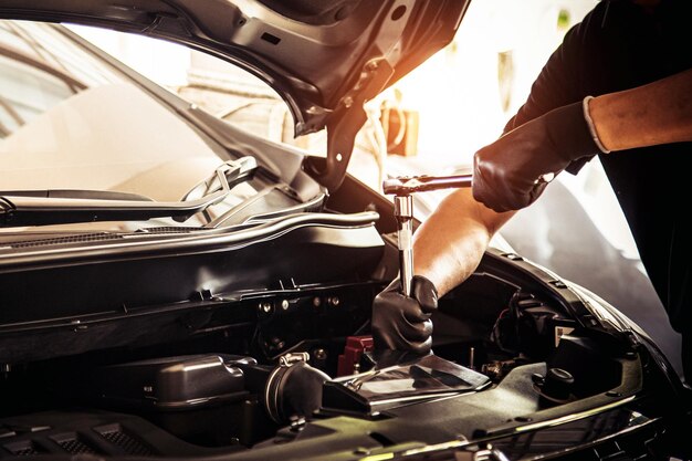 Mecânico de automóveis em close-up usando a chave inglesa para reparar um problema no motor do carro