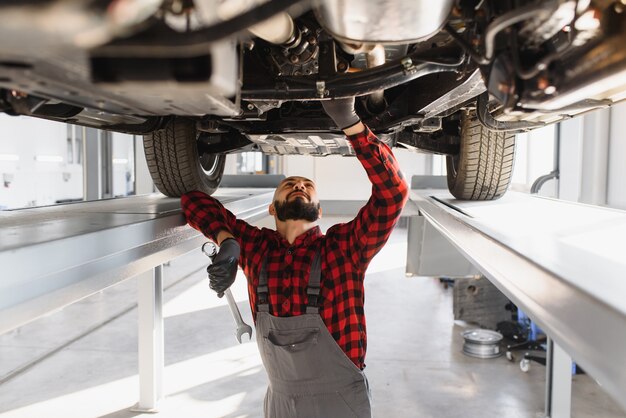 Foto mecânico de automóveis trabalhando embaixo de um carro levantado